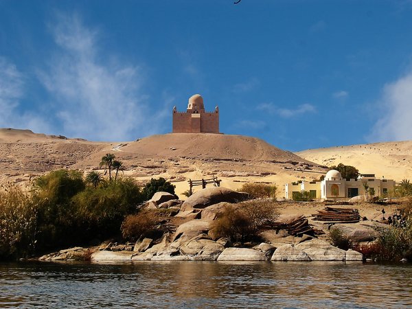 Mausoleo di Aga Khan ad Aswan con paesaggio desertico e cielo blu, visto dal fiume Nilo.