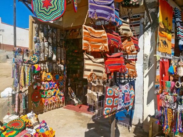 Colorful stall in Aswan Market with fabrics, bags, and traditional Egyptian crafts.