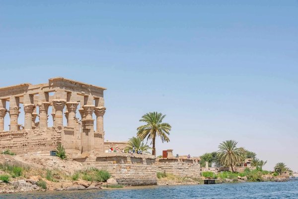 Ancient temple near the Nile River in Aswan, surrounded by palm trees and clear skies.