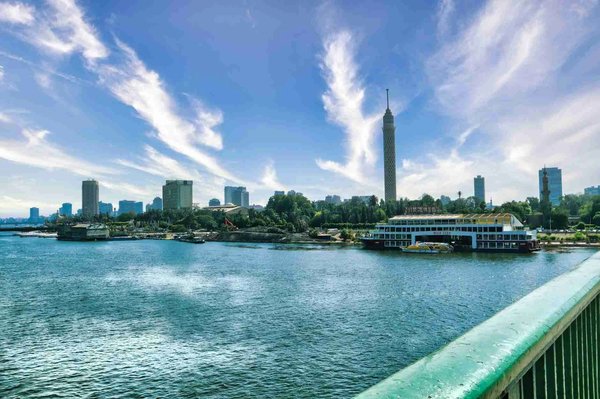 View of the Nile with the Cairo Tower and a romantic cruise, blue sky, and city skyline.