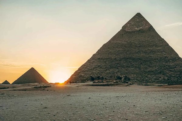 Sunset over the Pyramids of Giza in Cairo, with the sun setting behind the ancient structures.