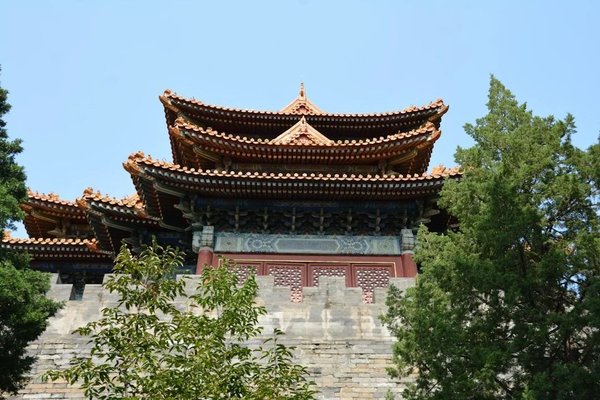 Traditional Chinese pavilion at the Summer Palace in Beijing, surrounded by trees and blue sky.