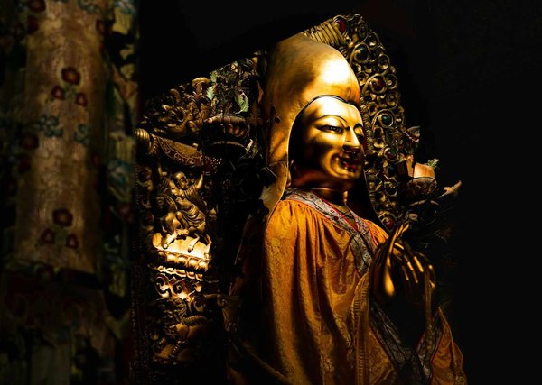 Golden statue decorated with intricate details in the Lama Temple in Beijing, illuminated by atmospheric light.