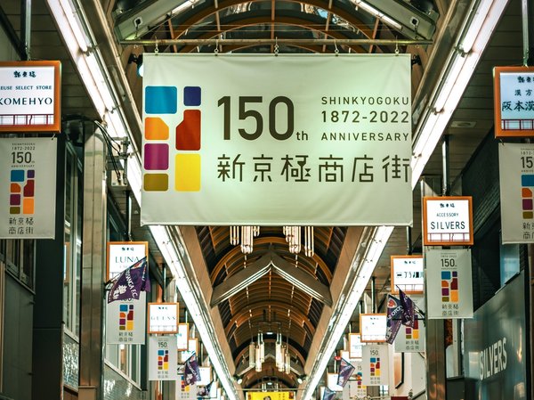 150th anniversary banner of Shinkyogoku, Teramachi Shopping Street, Kyoto, featuring bright signs and modern architecture.