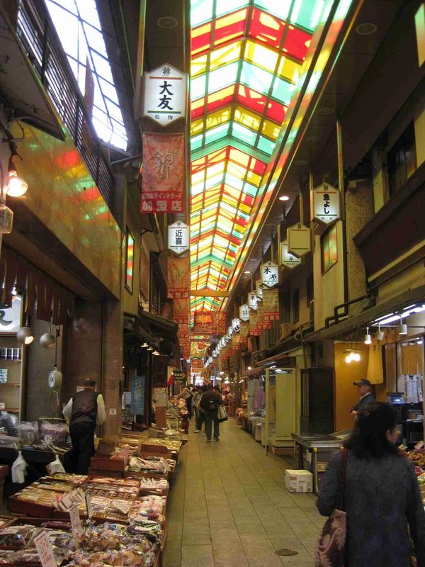 Nishiki Market in Kyoto with colorful ceiling and stalls of food and local products.
