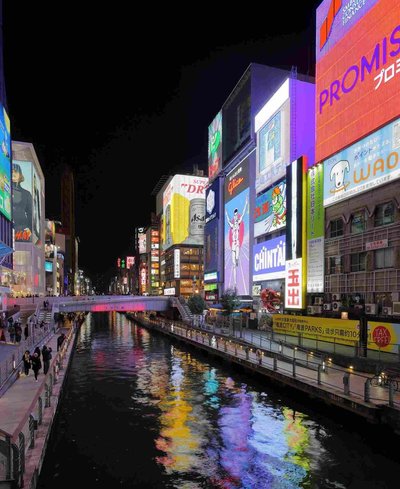 Night view of Dotonbori in Osaka with neon signs and reflections on the canal.