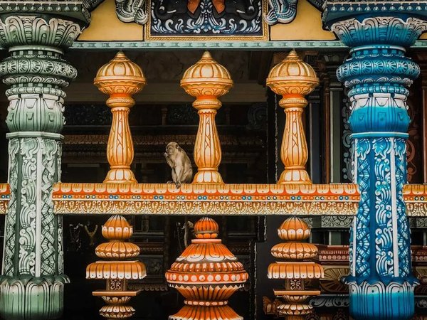 Colorful architectural detail of the Sri Mahamariamman Temple in Kuala Lumpur with a monkey sitting on a balustrade.