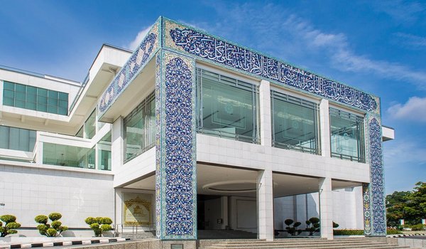 Facade of the Islamic Arts Museum in Kuala Lumpur with blue and white tile details under a clear blue sky.