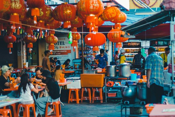 Vibrant scene of Chinatown in Kuala Lumpur with red lanterns and street food stalls.