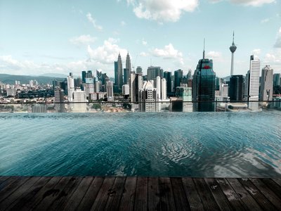 View of Kuala Lumpur skyline with Petronas Towers and KL Tower, reflected in an infinity pool.