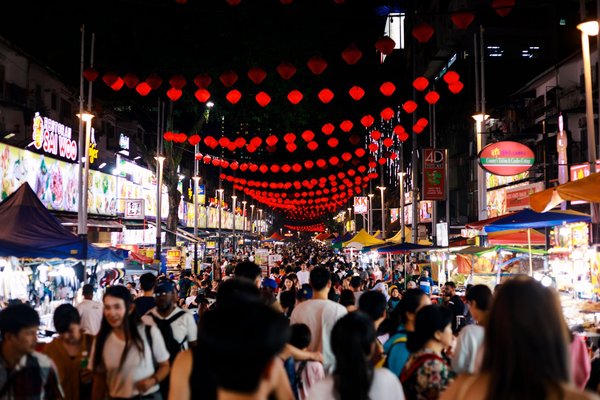 Jalan Alor Market in Kuala Lumpur with red lanterns, food stalls, and a bustling crowd of people at night.