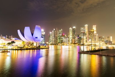 Night view of the ArtScience Museum and Singapore skyline reflected on the water.