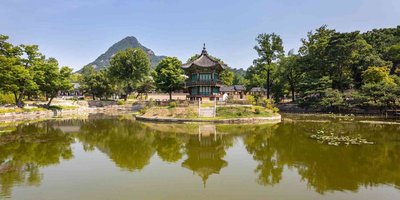 Vista panoramica del Padiglione Hyangwonjeong nel Palazzo Gyeongbokgung a Seoul con riflessi sull’acqua.