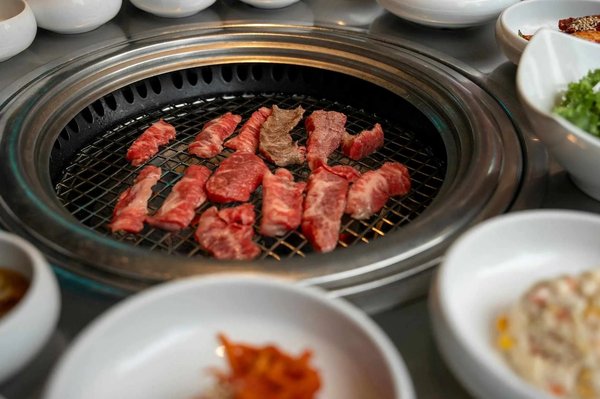 Carne alla griglia su barbecue coreano con contorni, esperienza iconica di Mapo Galbi a Seoul.