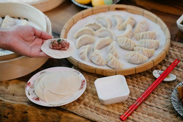 Preparazione di mandu fatti a mano con ripieno di carne a Bukchon Son Mandu, Seoul, su un tavolo tradizionale.