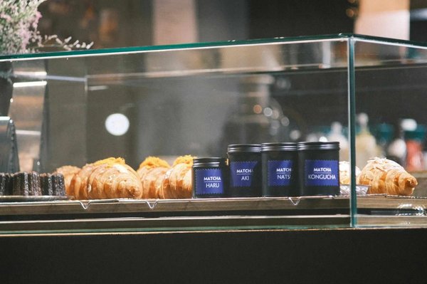 Vetrina con croissant, dolci e barattoli di tè matcha presso O'sulloc Tea House a Seoul.