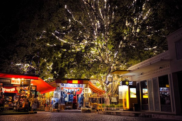 Chiang Mai Night Bazaar with illuminated stalls and trees adorned with lights, vibrant and welcoming atmosphere.