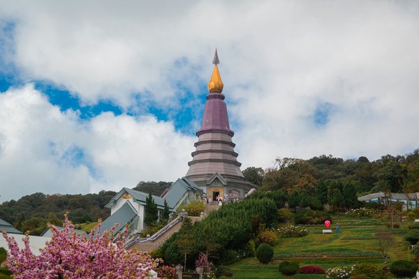 Iconic pagoda in Doi Inthanon National Park, Chiang Mai, surrounded by flowers and greenery under a blue sky.