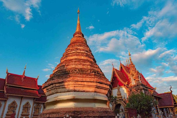 Wat Chedi Luang Temple in Chiang Mai with blue sky and golden architectural details.
