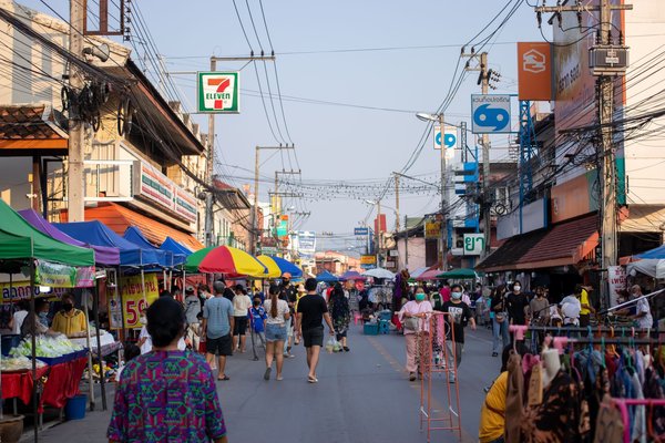 Street market with colorful stalls and people in Chiang Mai, Thailand.