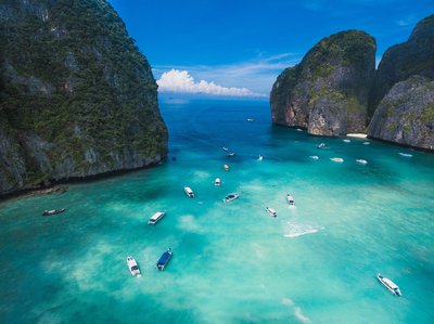 Aerial view of Maya Bay in Phuket with limestone cliffs, turquoise water, and boats.