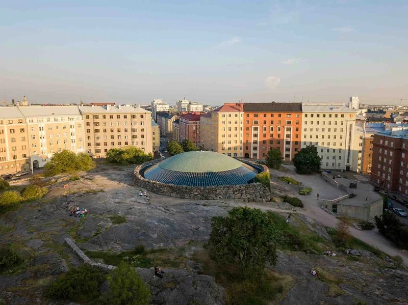 Vista aerea della Chiesa nella Roccia a Helsinki circondata da edifici e natura.