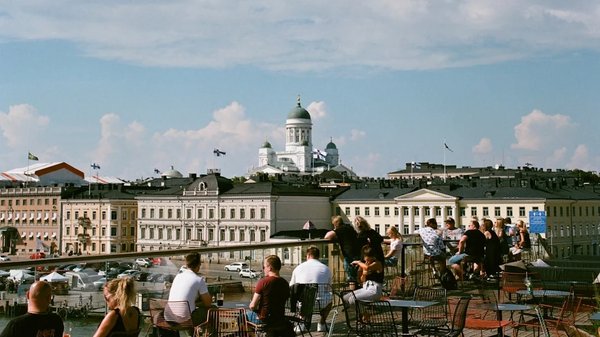 Vista della Cattedrale di Helsinki con persone sedute su una terrazza all'aperto in una giornata soleggiata.