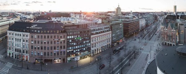 Vista panoramica di una strada nel Design District di Helsinki con edifici storici e moderni al tramonto.