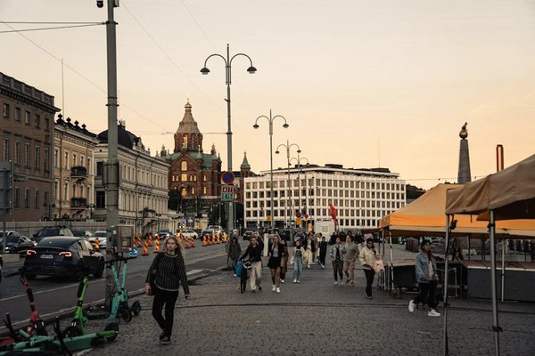 Vista di Helsinki con la Cattedrale Uspenski e tende del mercato al tramonto, persone che camminano per strada.