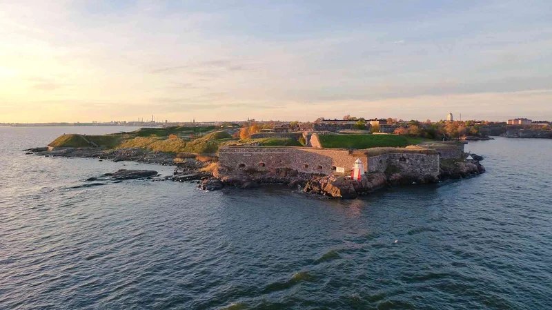 Veduta aerea dell'isola di Suomenlinna a Helsinki con fortificazioni storiche e mare al tramonto.