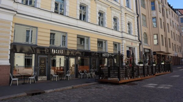 Ristorante locale a Helsinki con posti a sedere all'aperto e edificio storico sullo sfondo.