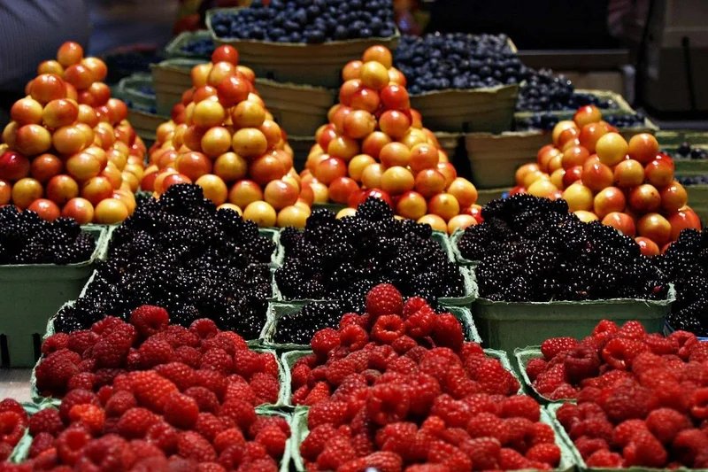 Bancarella di mercato con frutta fresca colorata, tra cui lamponi, more e prugne, a Noailles, Marsiglia.