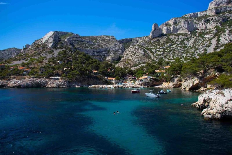 Vista delle Calanques vicino a Marsiglia con scogliere rocciose, acqua turchese e un villaggio costiero.