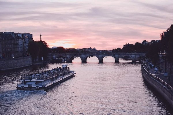 Boat tour on the Seine at sunset with a view of the Eiffel Tower and a historic bridge in Paris.