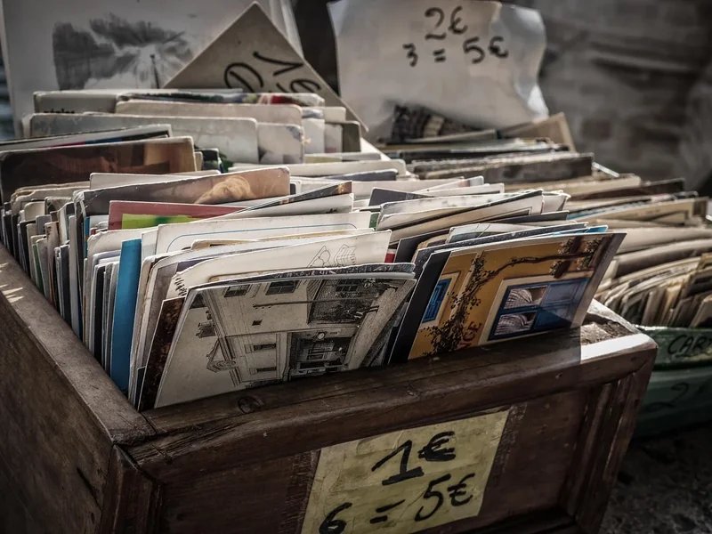 Box of vintage postcards for sale at the Saint-Ouen Flea Market, with visible euro price tags.