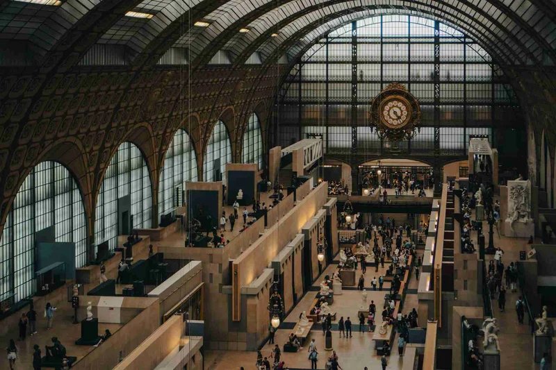 Interior of the Musée d'Orsay in Paris with the famous clock and visitors exploring the artworks.