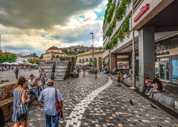 Monastiraki Square in Athens with a view of the Acropolis, historic buildings, and people walking.