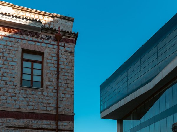 Architectural detail of the Acropolis Museum in Athens with modern and traditional buildings under a blue sky.