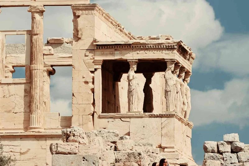 View of the Caryatids of the Erechtheion on the Acropolis of Athens with a blue sky in the background.