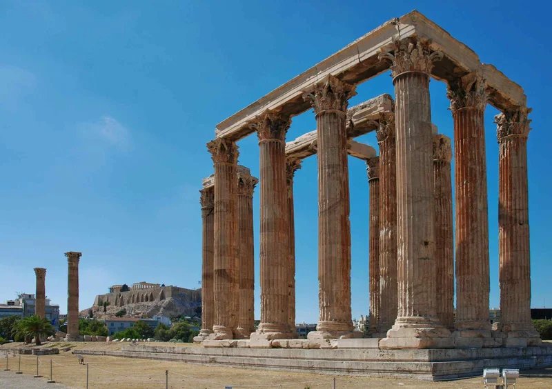 Temple of Olympian Zeus in Athens with a blue sky and ancient columns in the foreground.