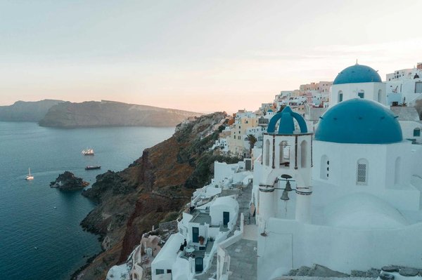 View of Oia in Santorini with blue domes, white buildings, and the sea at sunset.