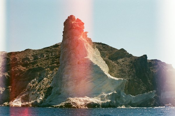 A striking reddish volcanic rock formation rising from the sea near Akrotiri's Red Beach.