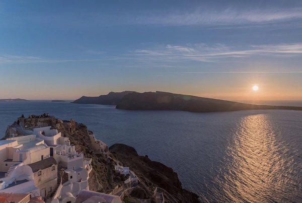 View of Santorini at sunset with white buildings and the Aegean Sea illuminated by the sun.