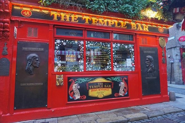 Facade of the Temple Bar in Dublin, with red signage and Christmas decorations, an iconic symbol of the Temple Bar district.