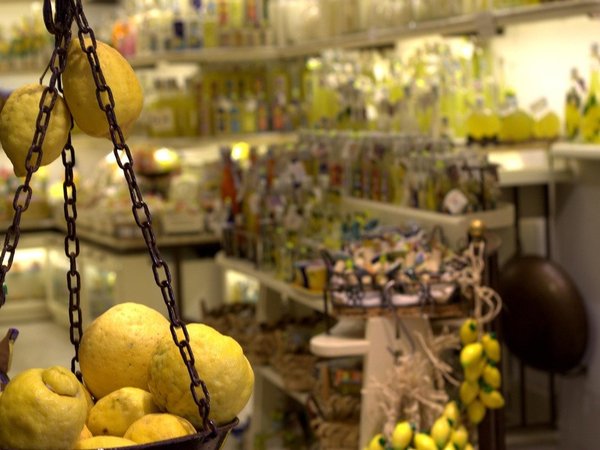 Fresh lemons on a scale with limoncello bottles in the background at a shop in Amalfi.