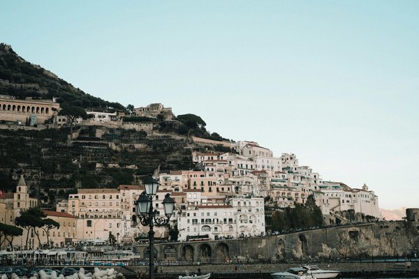 View of Amalfi coast with historic buildings and boats in the harbor.