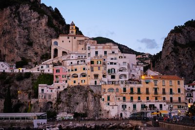 Panoramic view of Amalfi with colorful cliffside buildings at sunset.