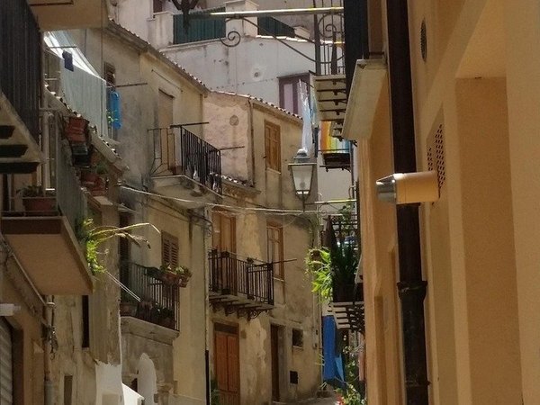 Narrow street with traditional buildings and flowered balconies in Amalfi, showcasing a typical Mediterranean vibe.