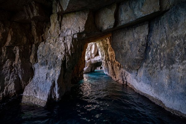 Interior of a sea cave with crystal-clear blue water and rocky walls illuminated by natural light in Capri.