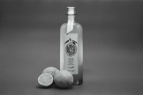Bottle of limoncello with fresh lemons on a monochromatic background.
